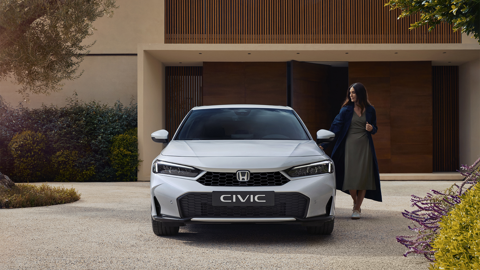 Ripresa frontale di una Civic Hybrid, con una donna che ne apre la portiera.