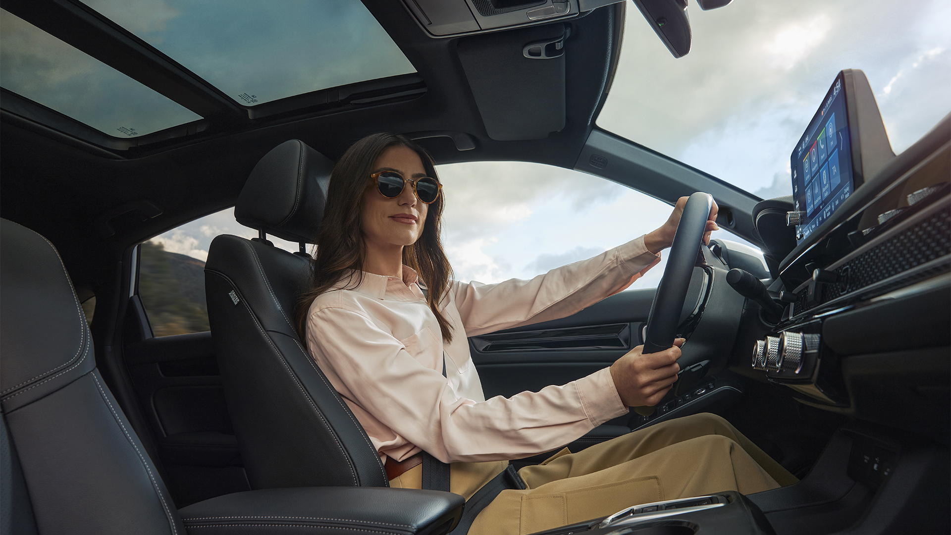 Una donna con occhiali da sole, con le mani sul volante della Civic Hybrid