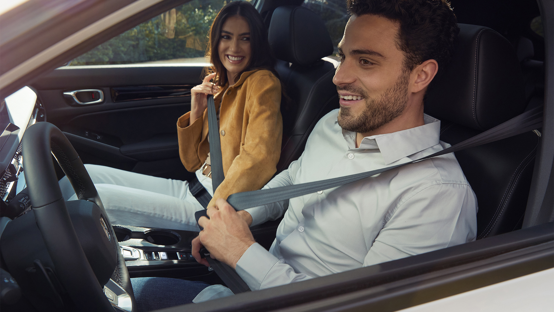 Due persone allacciano le cinture di sicurezza all'interno della Honda Civic Hybrid.