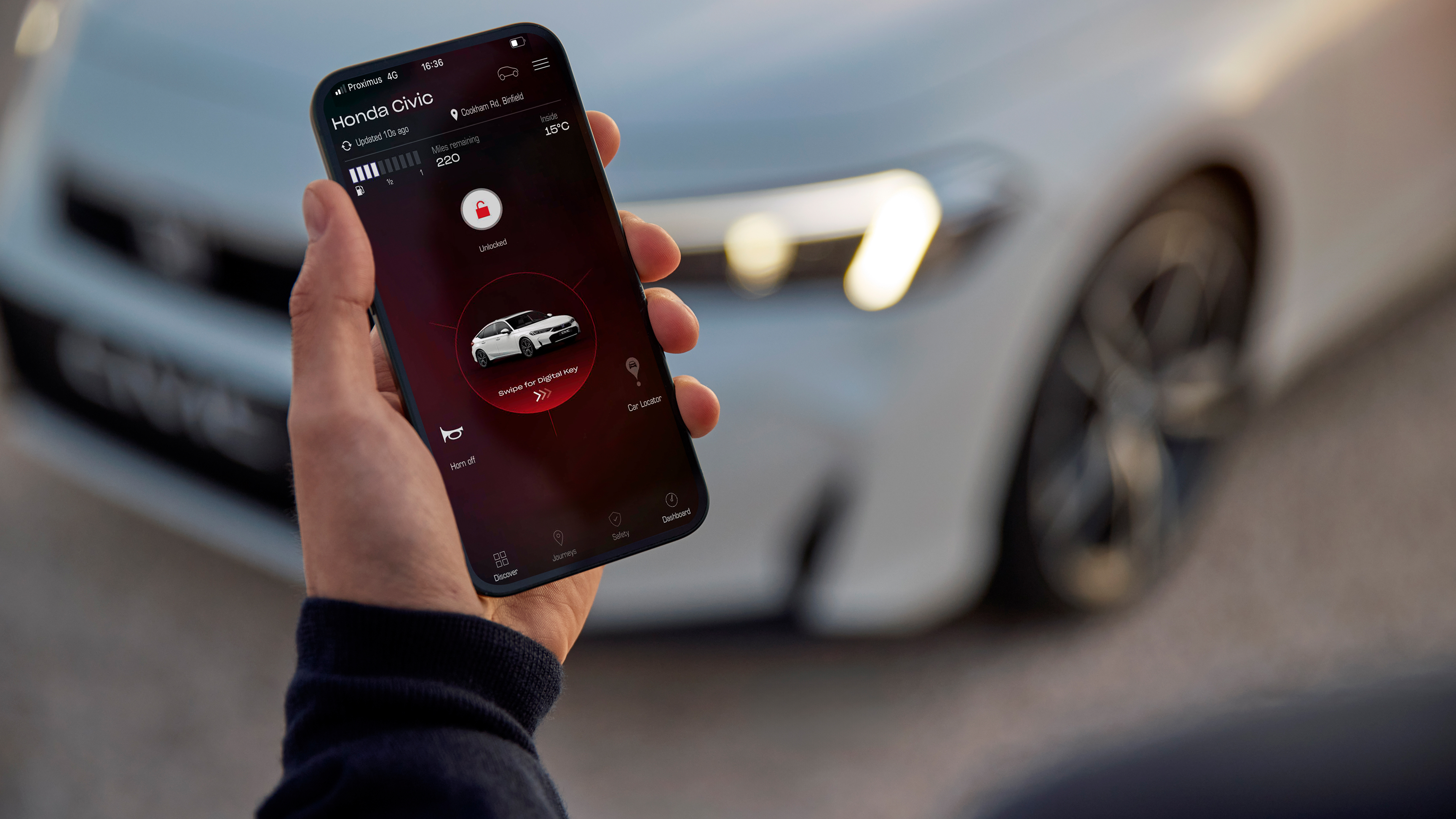 Una persona tiene in mano uno smartphone con My Honda+ app sullo schermo.