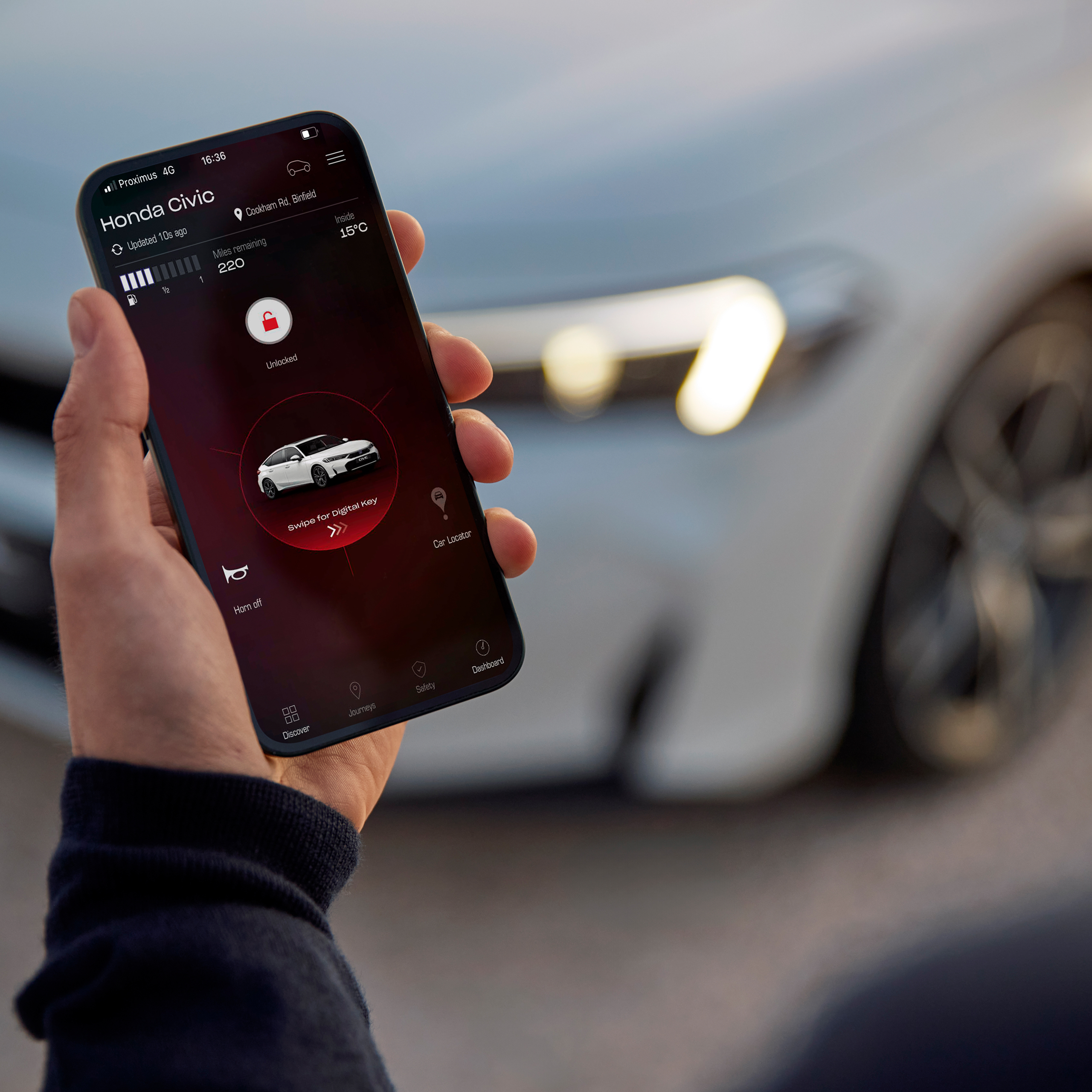 Una persona tiene in mano uno smartphone con My Honda+ app sullo schermo.