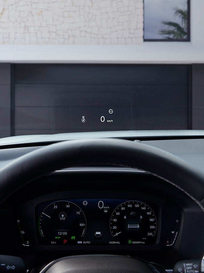 Una visuale in prima persona dal posto di guida che mostra un Head-Up Display (HUD) che proietta "50 km/h" e una bussola sul parabrezza sopra una strada sterrata.