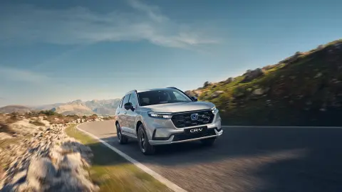 Vista frontale del SUV CR-V Hybrid in marcia in un ambiente montano.