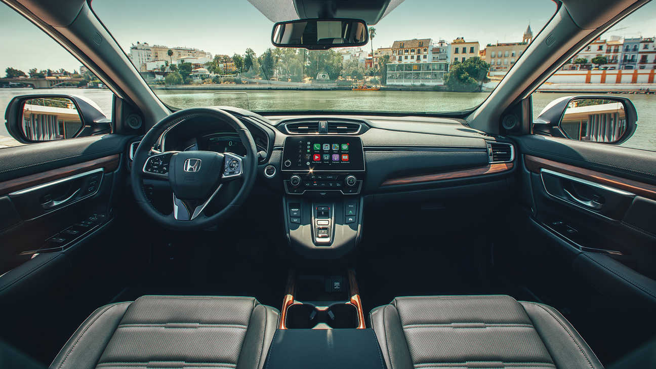 Primo piano del cruscotto interiore della Honda CR-V Hybrid che illustra l'ampia vista in una strada.