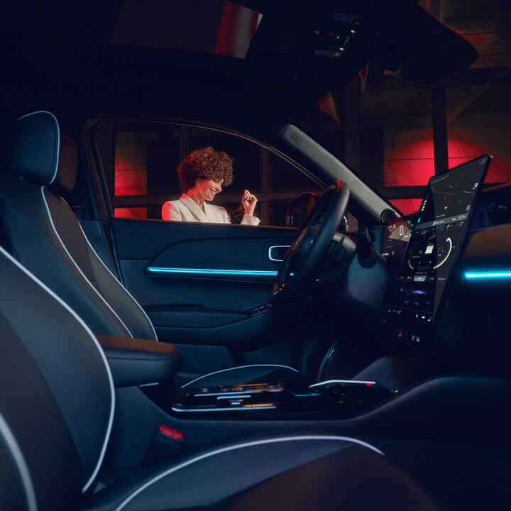 Interni illuminati di un Honda e:Ny1 di notte con un modello fuori dal finestrino.