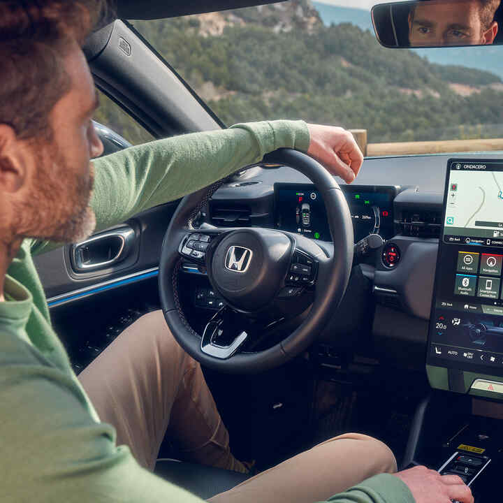 Uomo alla guida di un Honda e:Ny1 che utilizza la navigazione sul display digitale del conducente.
