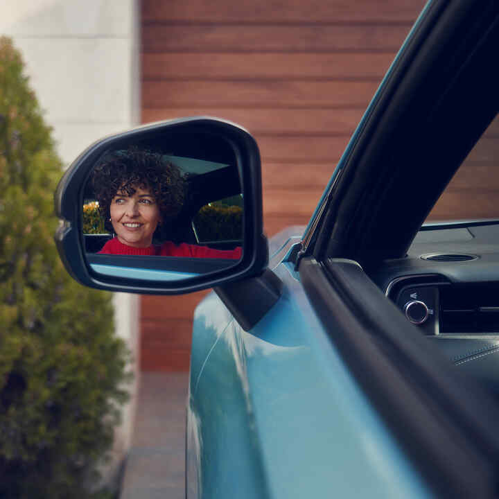 Riflesso di una donna nello specchietto retrovisore di un Honda e:Ny1.