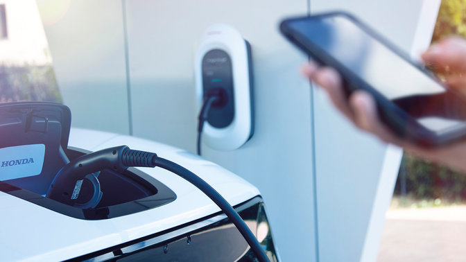 Modello che dimostra l'app My Honda+ mentre invia aggiornamenti sullo stato di carica.