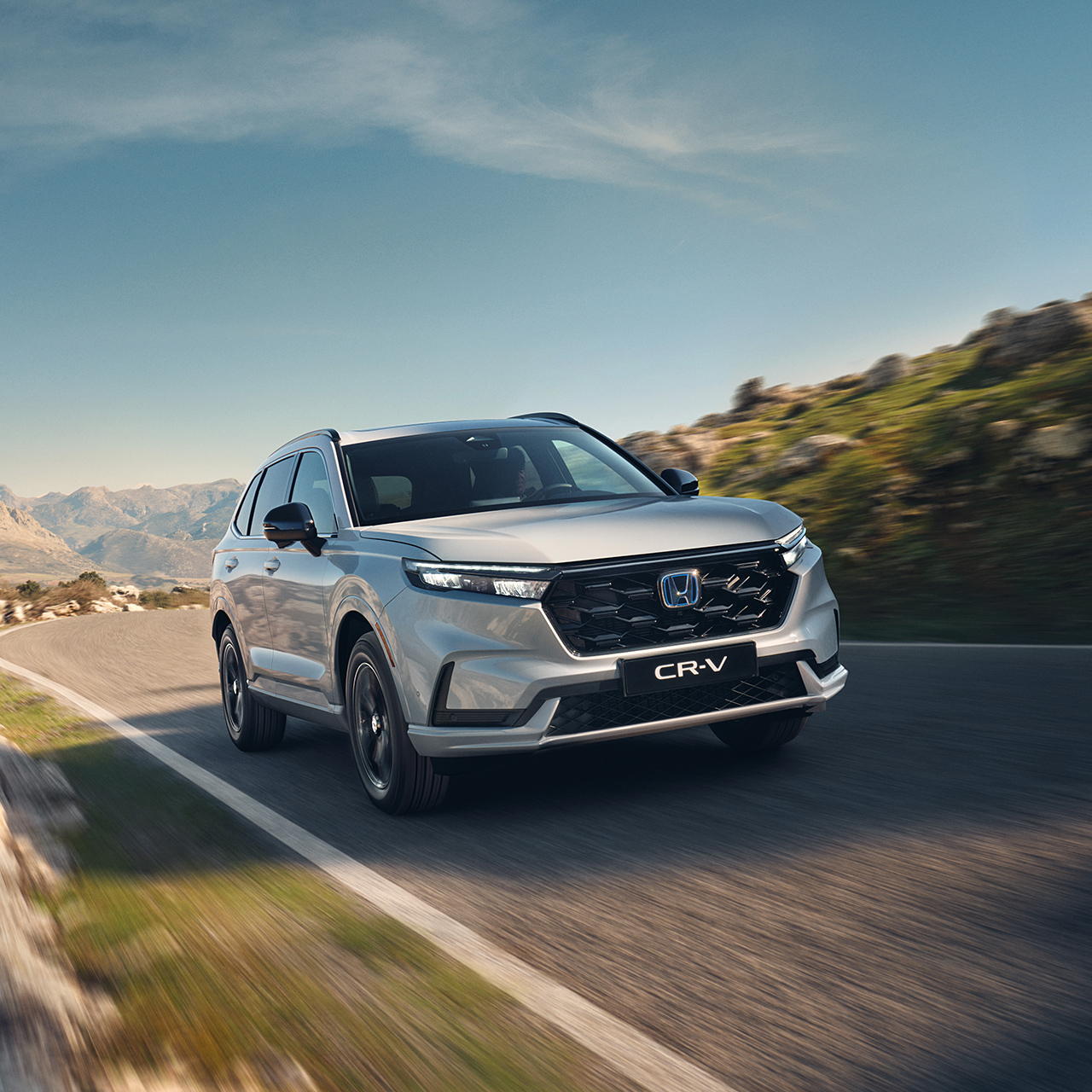 CR-V Plugin Hybrid di colore bianco in marcia su strada in un ambiente montano.