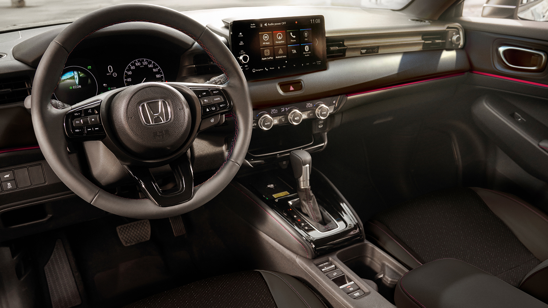 Vista interna di una Honda HR-V che mostra il volante, il quadro strumenti digitale, il touchscreen centrale e il selettore del cambio automatico.