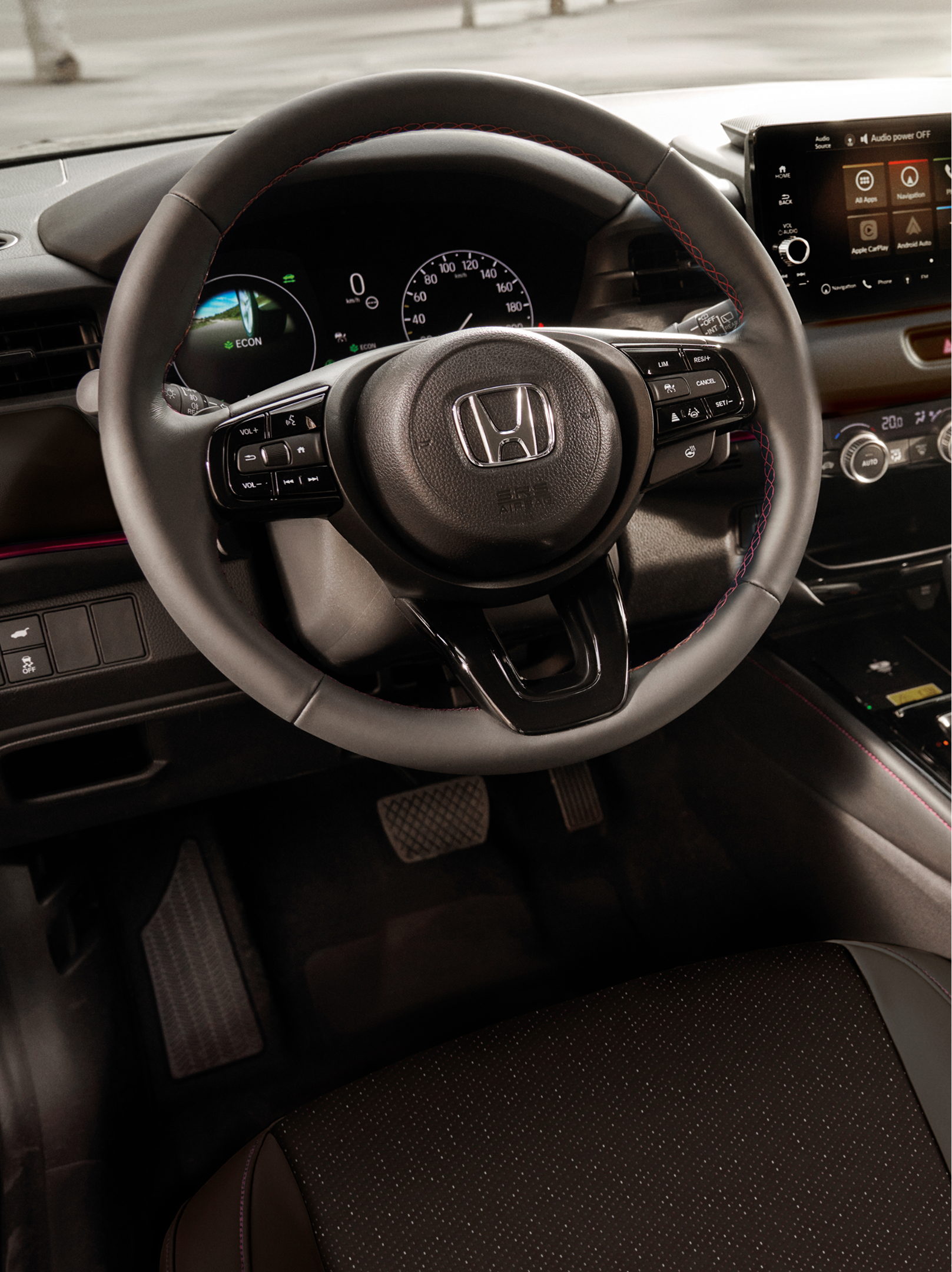 Vista interna di una Honda HR-V che mostra il volante, il quadro strumenti digitale, il touchscreen centrale e il selettore del cambio automatico.