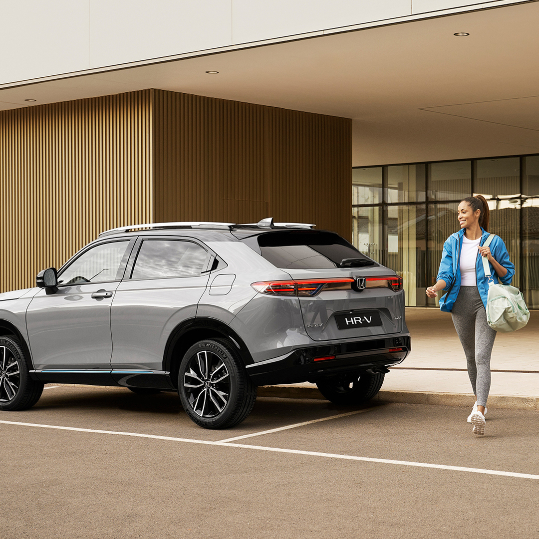 Donna che cammina a lato di un HR-V parcheggiato.