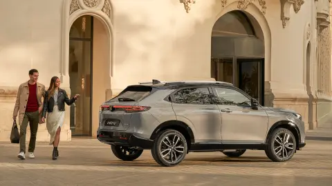 Vista laterale del Honda HR-V fuori da un hotel con una coppia che passa accanto. 