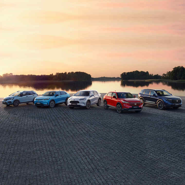 Gamma di veicoli ibridi Honda parcheggiati davanti a un paesaggio urbano