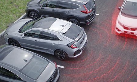 Honda Sensing car in a car park with illustration of cross traffic monitor and blind spot information.