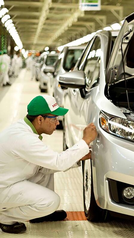 Tecnico Honda che lavora su un'auto in fabbrica.