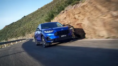 SUV Honda ZR-V Hybrid in marcia su strada in un ambiente montano.