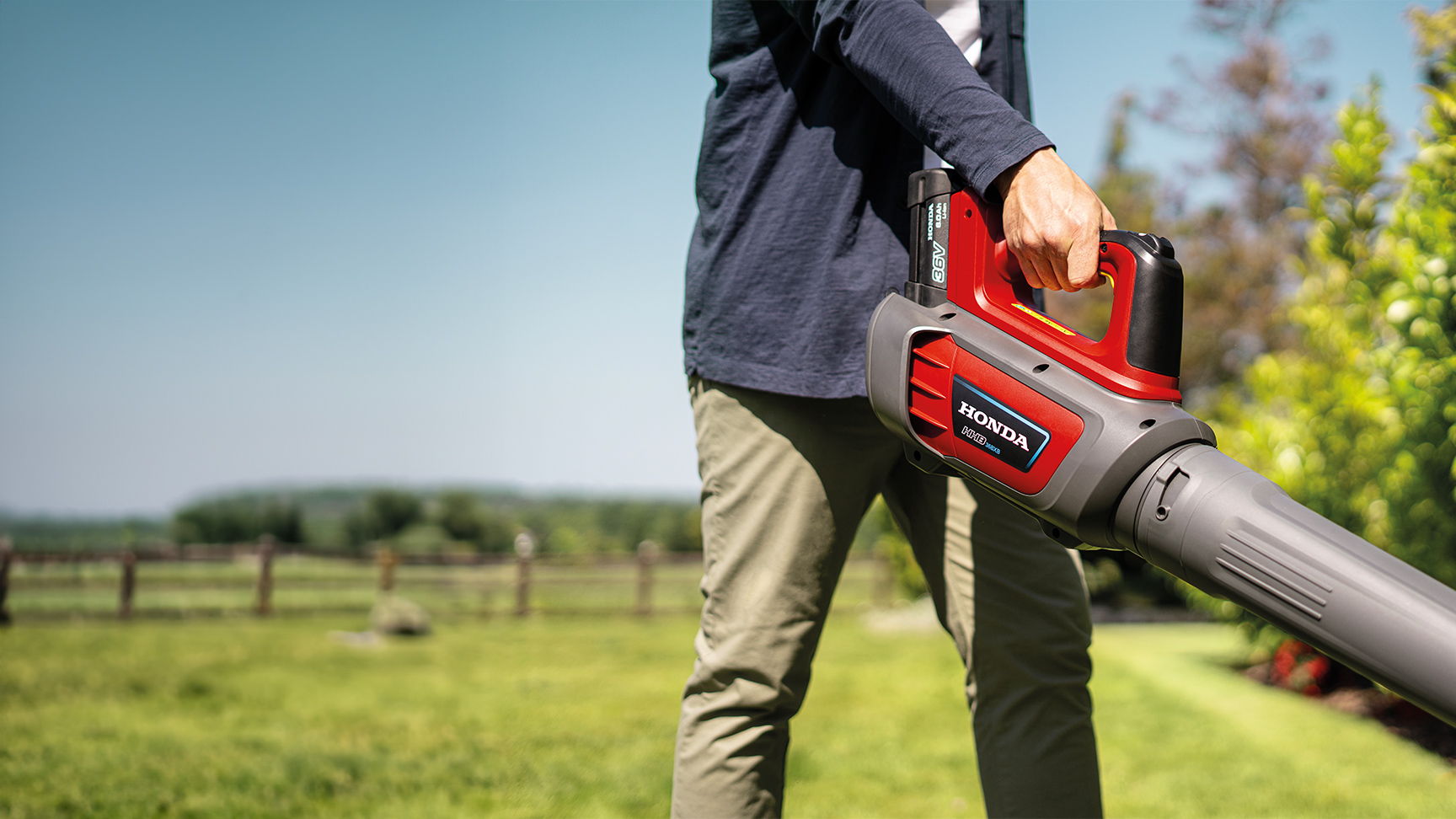 Uomo che utilizza un soffiatore a batteria in un giardino.