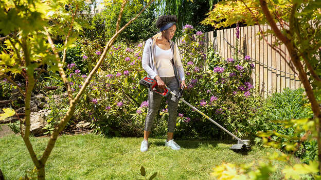 Donna in un giardino che utilizza il decespugliatore a batteria Honda.