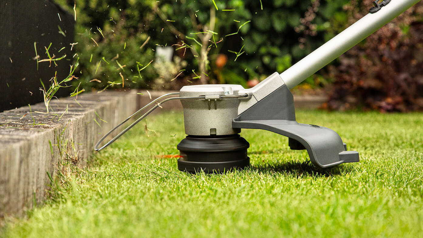 Un tagliaerba a batteria Honda taglia un lato dell'erba in un giardino.