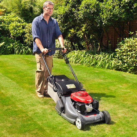 Inquadratura anteriore di tre quarti, rasaerba rivolto a destra, utilizzato da un modello, luogo di utilizzo: giardino.