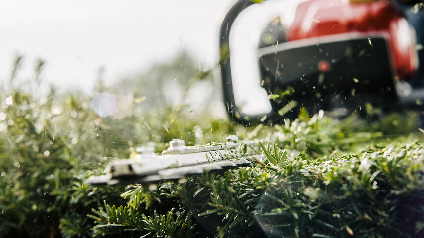 Uomo che usa un tagliasiepi con cuffie con cancellazione del rumore