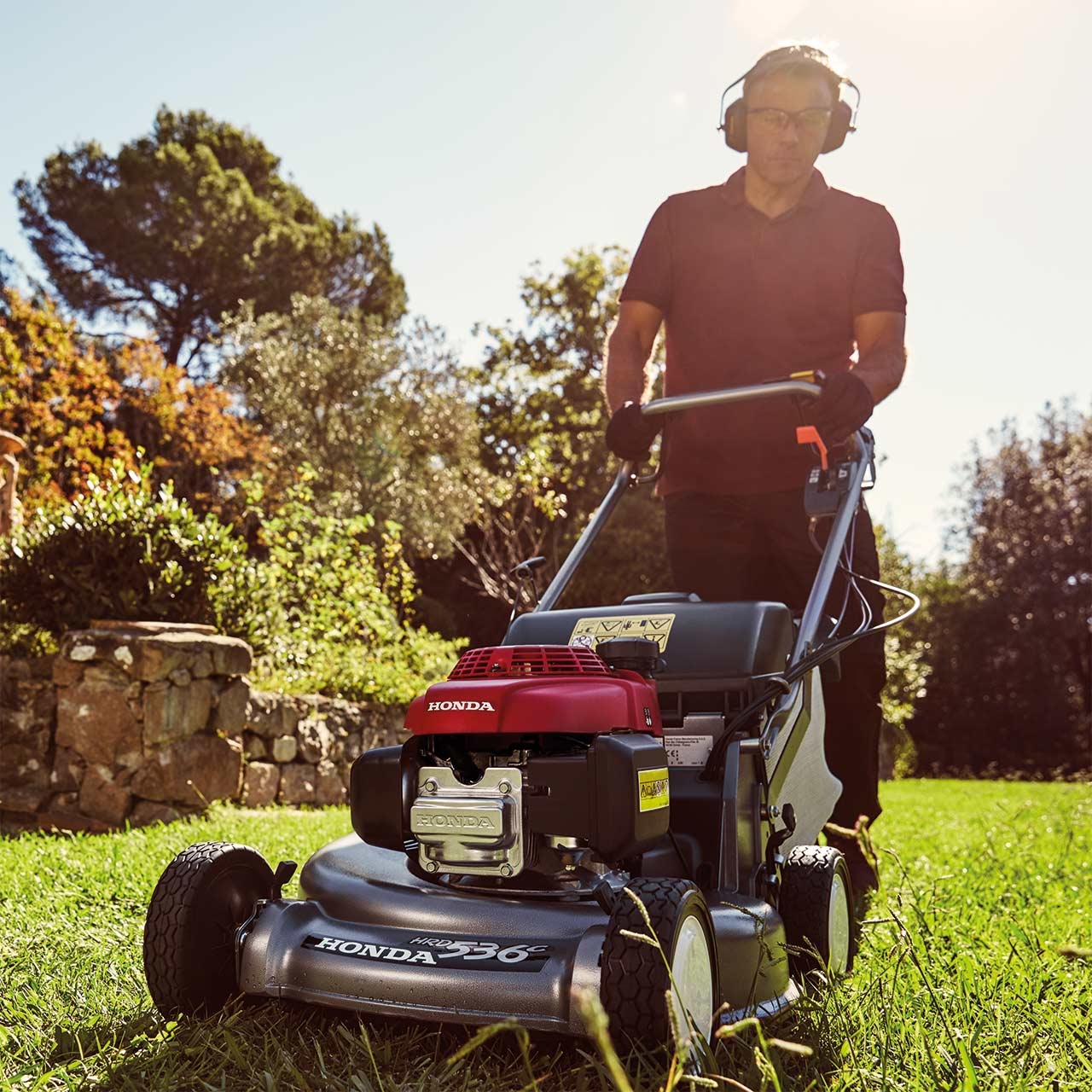 Uomo in giardino che taglia l'erba con un rasaerba Honda HRD.