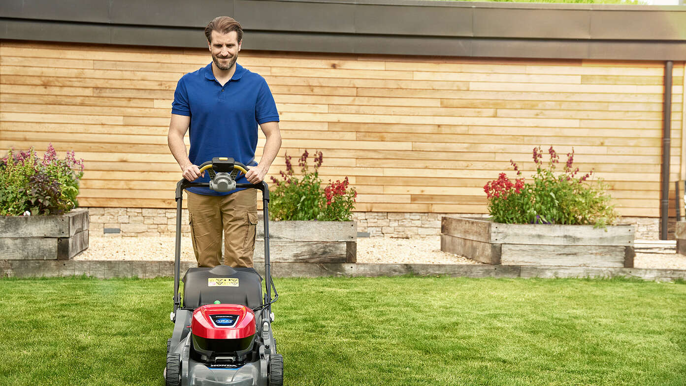 Uomo che spinge Honda HRX in giardino