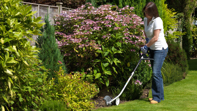 Honda Versatool con attrezzo tagliabordi, utilizzato da un modello, luogo di utilizzo: giardino.