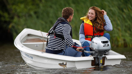 Una coppia sorridente in barca su un lago.