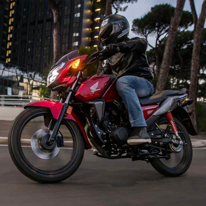 Vista anteriore di tre quarti sinistra della CB125F rossa su strada in un ambiente urbano