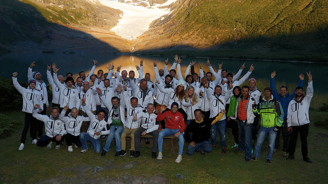 Partecipanti di Honda Adventure Roads che festeggiano in riva all'acqua al tramonto.