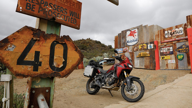 Honda CRF1000L Africa Twin parcheggiata presso una stazione di servizio lungo la strada.