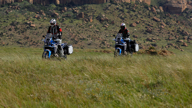 Due motociclisti Honda Adventure Roads in fuoristrada con le montagne sullo sfondo
