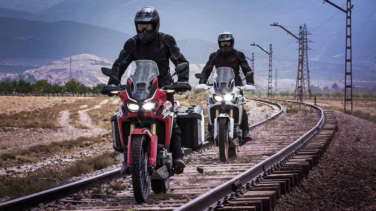 Due motociclette Honda Africa Twin percorrono i binari di una ferrovia