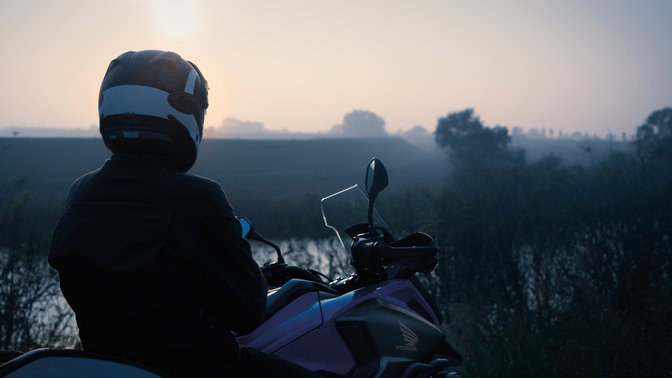 Conducente a cavallo di una Honda NC750X, parcheggiata in un luogo rurale.