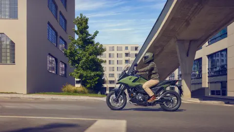 Vista laterale di un modello alla guida della moto NC750X in un contesto urbano.
