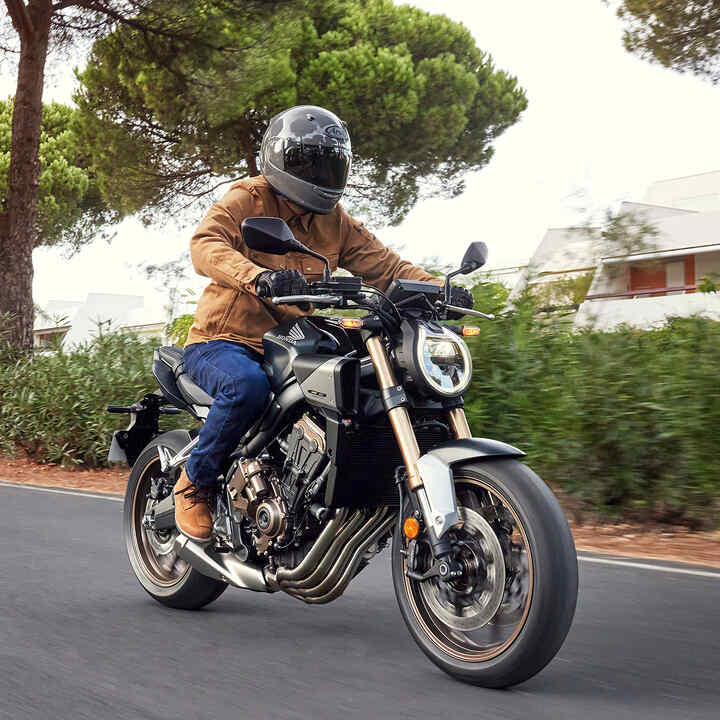 Modello in sella a una moto in una località di montagna.