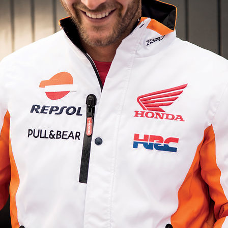 Uomo che sorride con indosso una giacca racing di Honda.