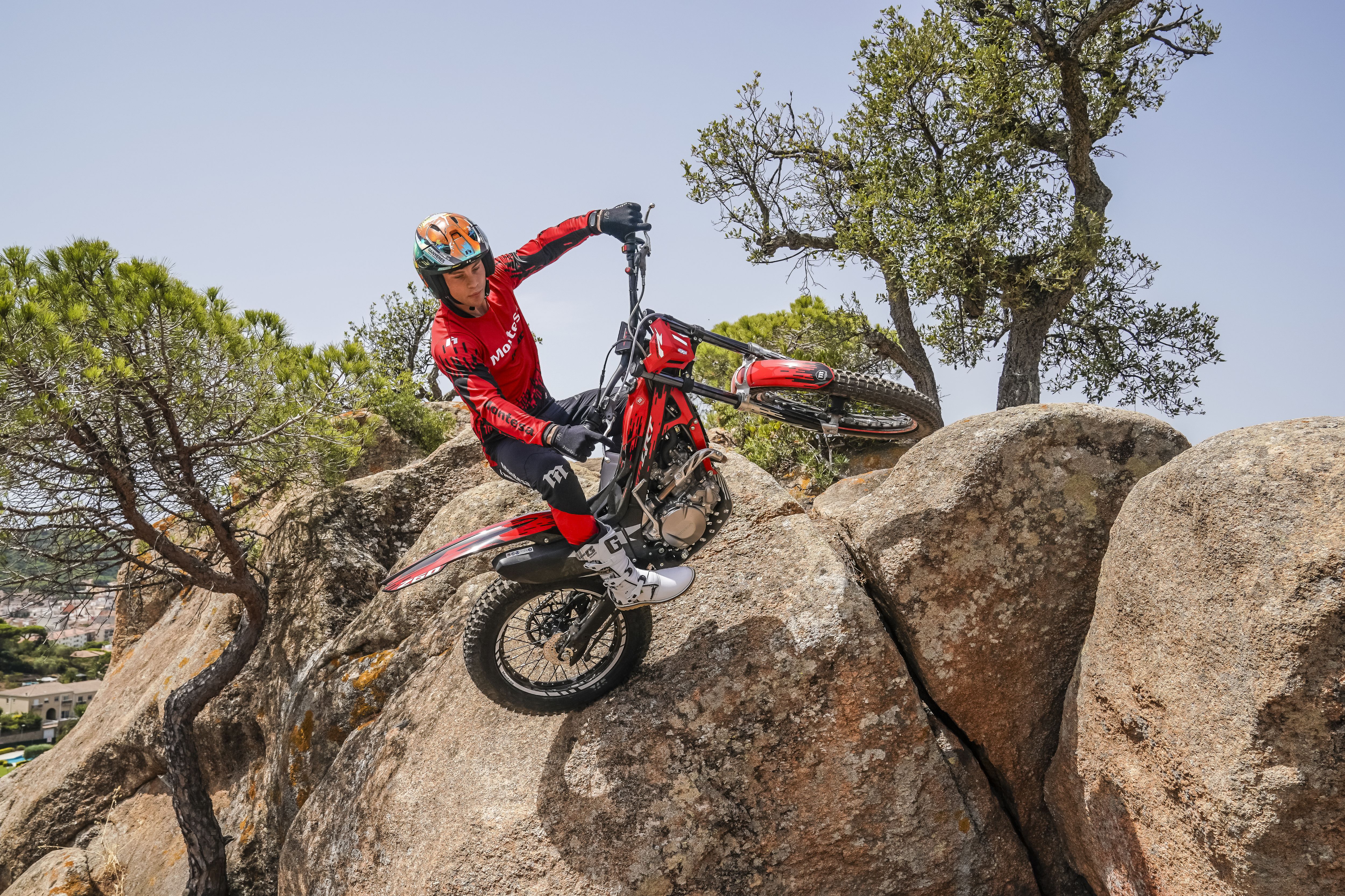 Un pilota supera dei ripidi massi con Montesa Cota 4RT 260R rossa in una giornata di sole.
