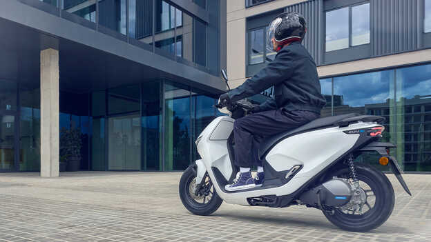 Modella alla guida di una moto elettrica Honda CUV e: che mostra la facilità di utilizzo della retromarcia.