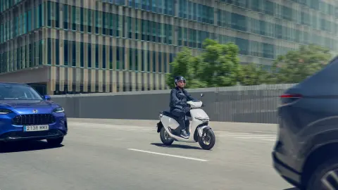 Motociclista alla guida di uno scooter elettrico Honda CUV e: in un contesto urbano.