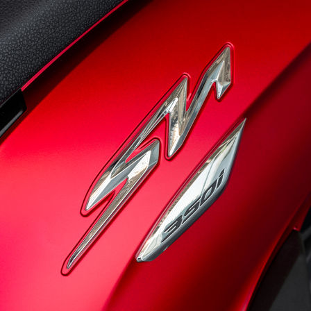 Honda SH350i, primo piano sul logo SH, moto rossa