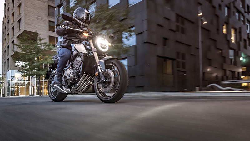 CB650R Neo Sports Café, vista di 3/4 destra con guidatore, in ambiente urbano