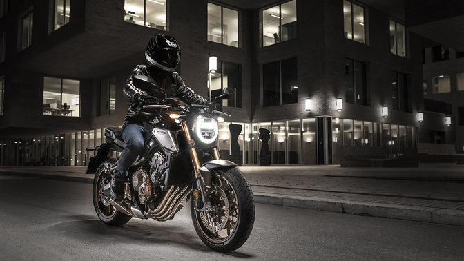 CB650R Neo Sports Café, vista di 3/4 frontale destra con guidatore, di notte in ambiente urbano