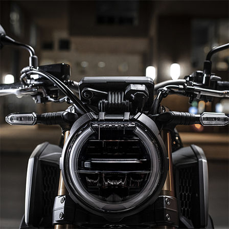 CB650R Neo Sports Café, vista frontale, dettaglio del faro anteriore, di notte in ambiente urbano 