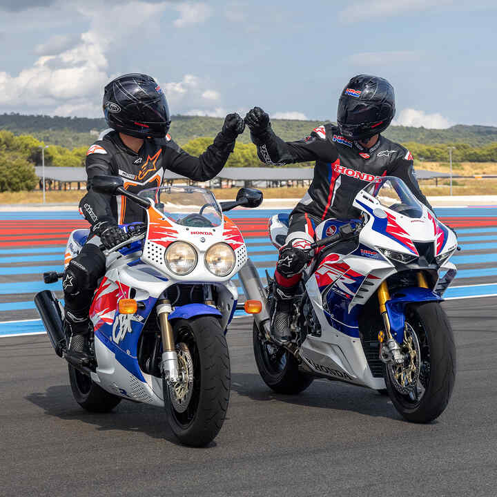 Due piloti seduti su Fireblades poste una di fronte all'altra che si battono i pugni in pista.