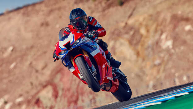 Pilota su Honda CBR1000RR-R Fireblade in pista con la ruota anteriore alzata.