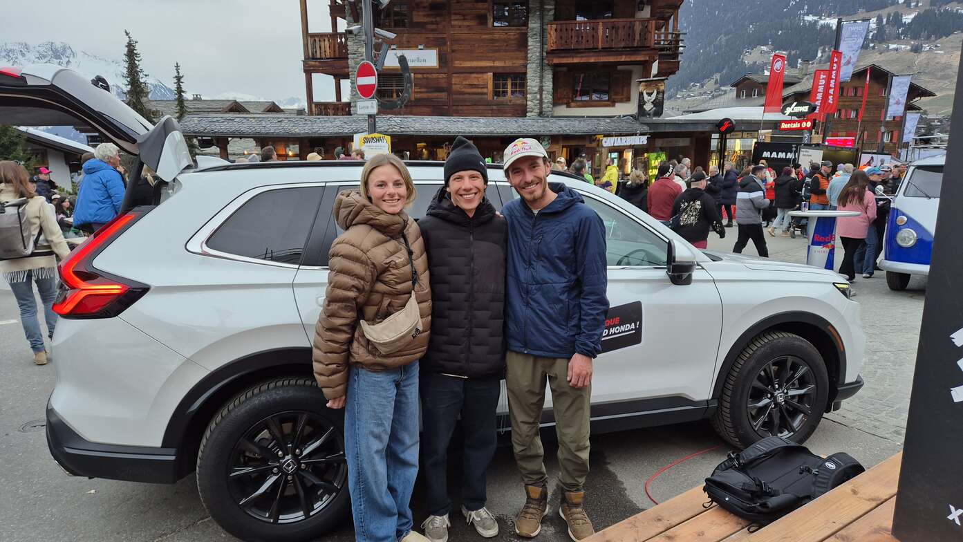 Tre freerider in posa davanti alla Honda CR-V ibrida allo stand Honda a Verbier.