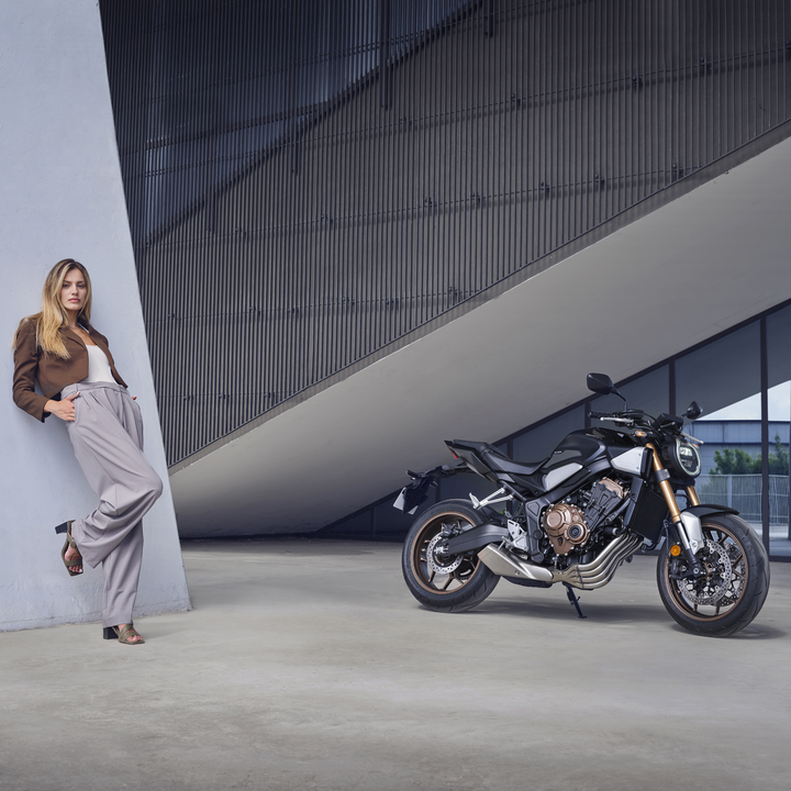 Modella appoggiata a un muro, accanto a una Honda CB650R